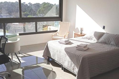 1 dormitorio con 1 cama, 1 silla y 1 ventana en Monomabiente amplio con piscina en Punta del Este