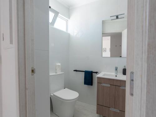 La salle de bains blanche est pourvue de toilettes et d'un lavabo. dans l'établissement Cosy beach apartment in Albufeira centre, à Albufeira
