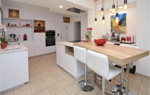 une cuisine avec une table en bois et des armoires blanches dans l'établissement Amazing Home In Nîmes, à Nîmes