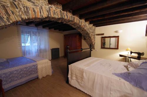 a bedroom with two beds and a stone wall at Il Mulino del Castello in Garlenda