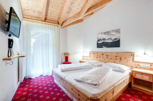 a bedroom with a large bed and a television at Hotel Klostersepp - Neu in Chiusa