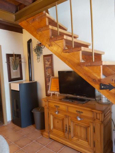 a living room with a tv on a wooden cabinet and a staircase at El Rincón de Pirón in Losana de Pirón