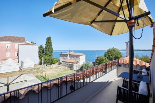 balcón con sombrilla y vistas al océano en Martis Forum Heritage Hotel & Residence en Poreč