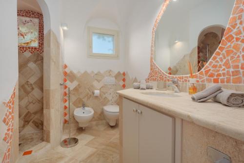 ein Badezimmer mit einem WC, einem Waschbecken und einem Spiegel in der Unterkunft Villetta d'Arancia - SHERDENIA Luxury Apartments in Marinella