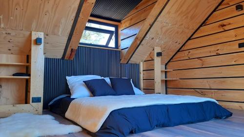 a bedroom with a bed in a wooden cabin at El Contemplatorio in Tiltil