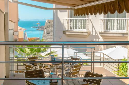balcón con mesa, sillas y vistas al océano en Hotel Atalaya II, en Portonovo