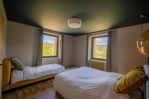 a bedroom with two beds and two windows at Le 11 des Bouchaux, Gîte d'exception in La Bresse