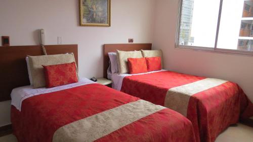 a bedroom with two beds with red and white sheets at Hotel Zulita in Bogotá