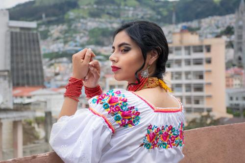 a woman in a mexican dress standing on a building at Chakana Hotel Boutique Centro in Quito