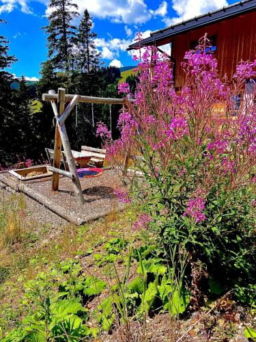 a garden with purple flowers and a wooden bench at Almhütte in Lachtal