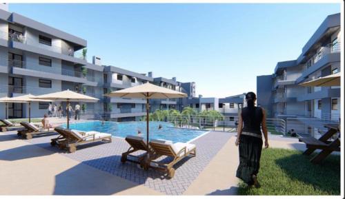 a man is standing in front of a swimming pool at NIVICA Lifestyle Apartments in Langebaan