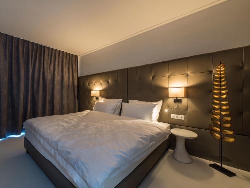 Un dormitorio con una cama grande y dos lámparas. en Merangardenvilla adults only, en Merano
