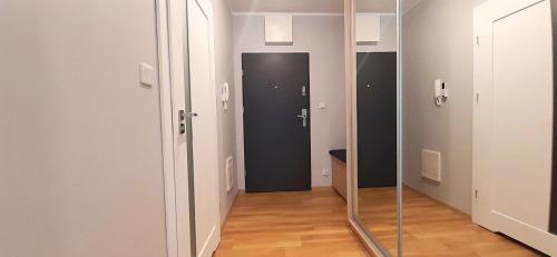 a hallway with a glass door and a mirror at Masurian Apartments in Mrągowo