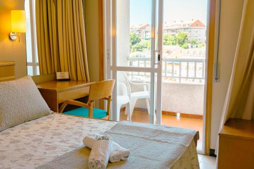 a hotel room with a bed and a desk and a balcony at Hotel Atalaya I in Portonovo