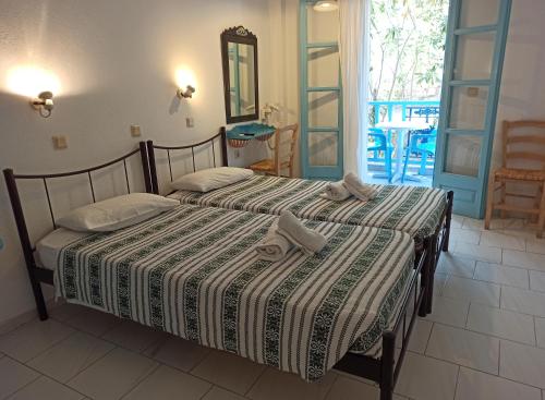 two beds in a room with a table and chairs at Daidalos Hotel in Armenistis