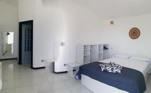 een witte slaapkamer met een bed en een spiegel bij Sulcis Camere in San Giovanni Suèrgiu