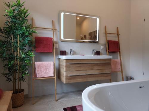 ein Badezimmer mit einer Badewanne, einem Waschbecken und einem Spiegel in der Unterkunft TYROL PURElife Lodges in Sankt Jakob in Defereggen