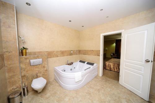 a bathroom with a tub and a toilet and a sink at Бутиков хотел History in Haskovo