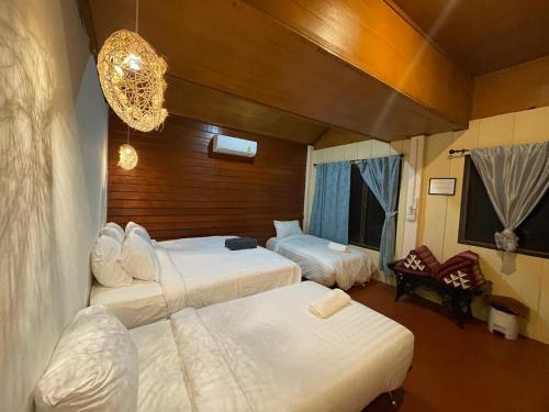 una camera d'albergo con tre letti e un lampadario a braccio di Marina Resort Koh Phayam Ranong a Ko Phayam