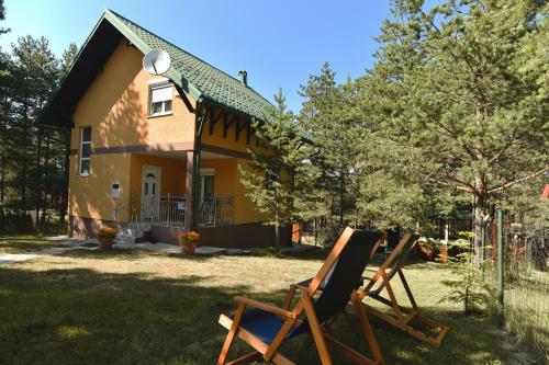 two rocking chairs in front of a yellow house at Vila ZLATNI BOR in Zlatibor