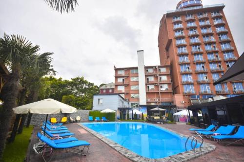 uma piscina com espreguiçadeiras e um hotel em Hotel Genatsvale em Batumi