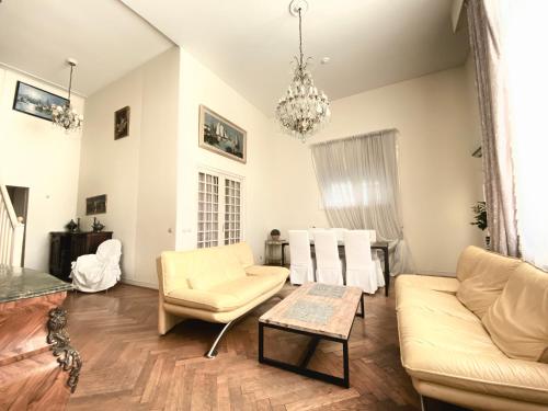 Elle comprend un salon doté d'un mobilier blanc et d'un lustre. dans l'établissement Duplex à la Villa Canteraine, à Cannes