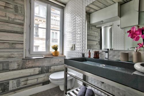 a bathroom with a sink and a toilet and a window at 1 Bedroom Le Marais Temple in Paris