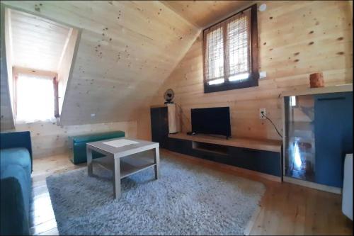 Cabaña con sala de estar con sofá y TV. en Kremanski čardak, en Kremna