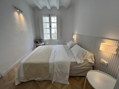 a white bedroom with a large bed and a window at The MO GOTIC in Barcelona