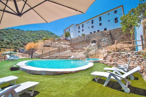 a swimming pool with lawn chairs and an umbrella at Hotel Almejí in Benadalid