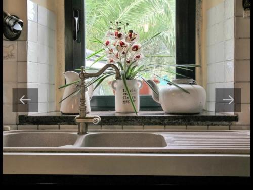 - un évier de cuisine avec 2 vases et une fenêtre dans l'établissement Villa vacanze floriana, à SantʼAngelo in Lizzola