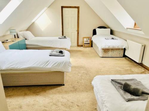 a attic room with three beds and a staircase at Grantham House in Grantham