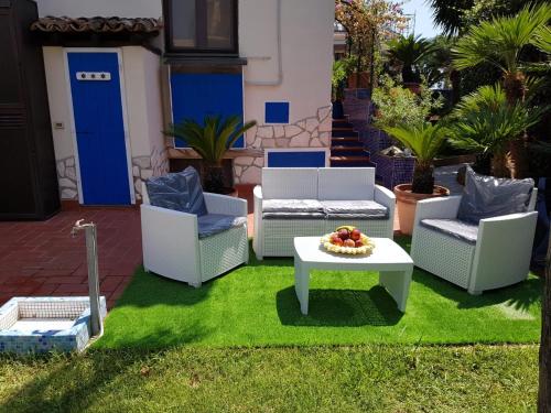 a patio with chairs and a table on grass at Villa Captains in Formia