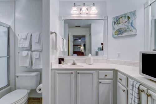 a bathroom with a sink and a toilet and a mirror at Omni Amelia Island Private Room at Courtside Villa-Minutes to Beach and Dining-2358 Boxwood Ln in Fernandina Beach