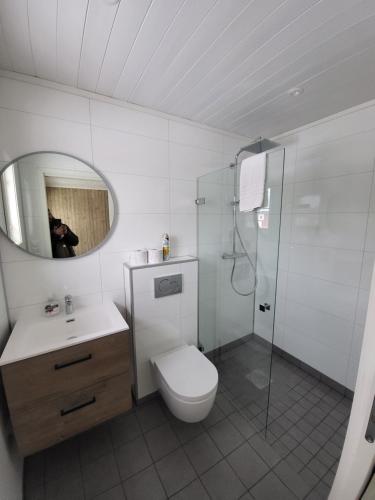 a white bathroom with a toilet and a shower at Å Rorbuer - by Classic Norway Hotels in Å