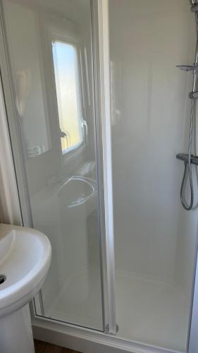 a white bathroom with a shower and a sink at Newquay Bay Resort 181 in Newquay Bay Resort