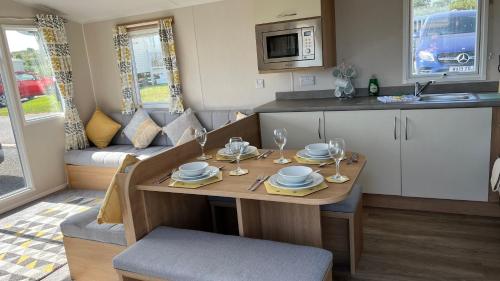 a small kitchen with a table with plates and wine glasses at Newquay Bay Resort 181 in Newquay Bay Resort