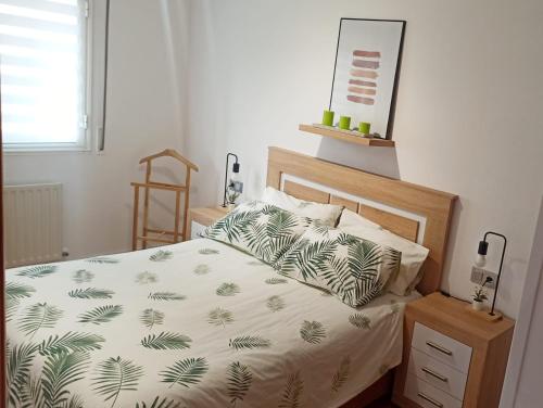 a bedroom with a bed with a white and green blanket at Apartamento en San Sebastián con parking in Loyola