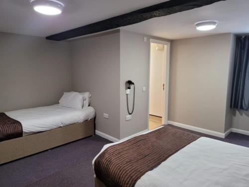 a bedroom with two beds and a phone on the wall at The Oakwood Hotel in Gloucester