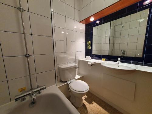 a bathroom with a toilet and a sink and a tub at The Oakwood Hotel in Gloucester