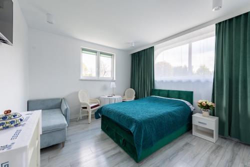 a bedroom with a green bed and a couch at Noclegi Biała Róża in Bolesławiec