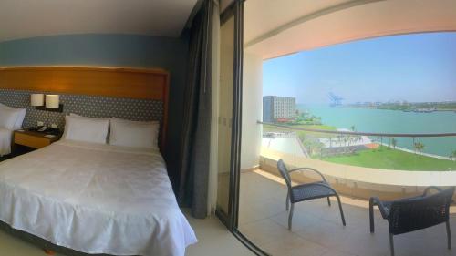 a bedroom with a bed and a balcony with a view at Holiday Inn Tuxpan - Convention Center by IHG in Tuxpan de Rodríguez Cano