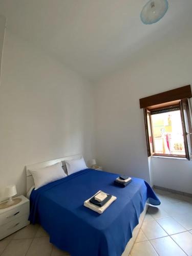 a blue bed in a white room with a window at ALMA FLEGREA in Bacoli