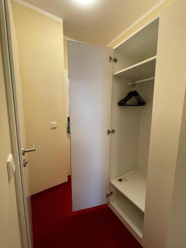 a walk in closet with a white door and red carpet at Palm Premium Hotel & Apartments in Düsseldorf
