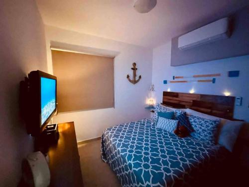 um quarto com uma cama e uma televisão de ecrã plano em Departamento Retro pv em Puerto Vallarta