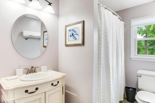 a white bathroom with a sink and a mirror at Pine Whiff Gardens in Annapolis