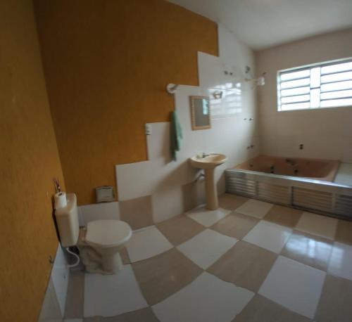 a bathroom with a toilet and a bath tub at Piratininga Guesthouse Casa de Hóspedes in Niterói