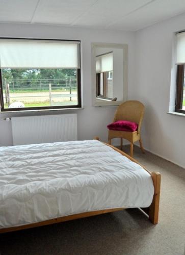 a bedroom with a bed and a chair and a window at 'T Bakhuusje in Putten