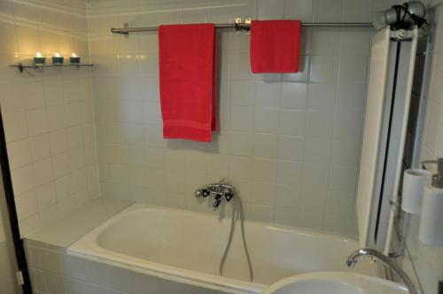 een badkamer met een wit bad en rode handdoeken bij 'T Bakhuusje in Putten