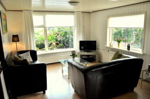 a living room with two leather chairs and a television at 'T Bakhuusje in Putten